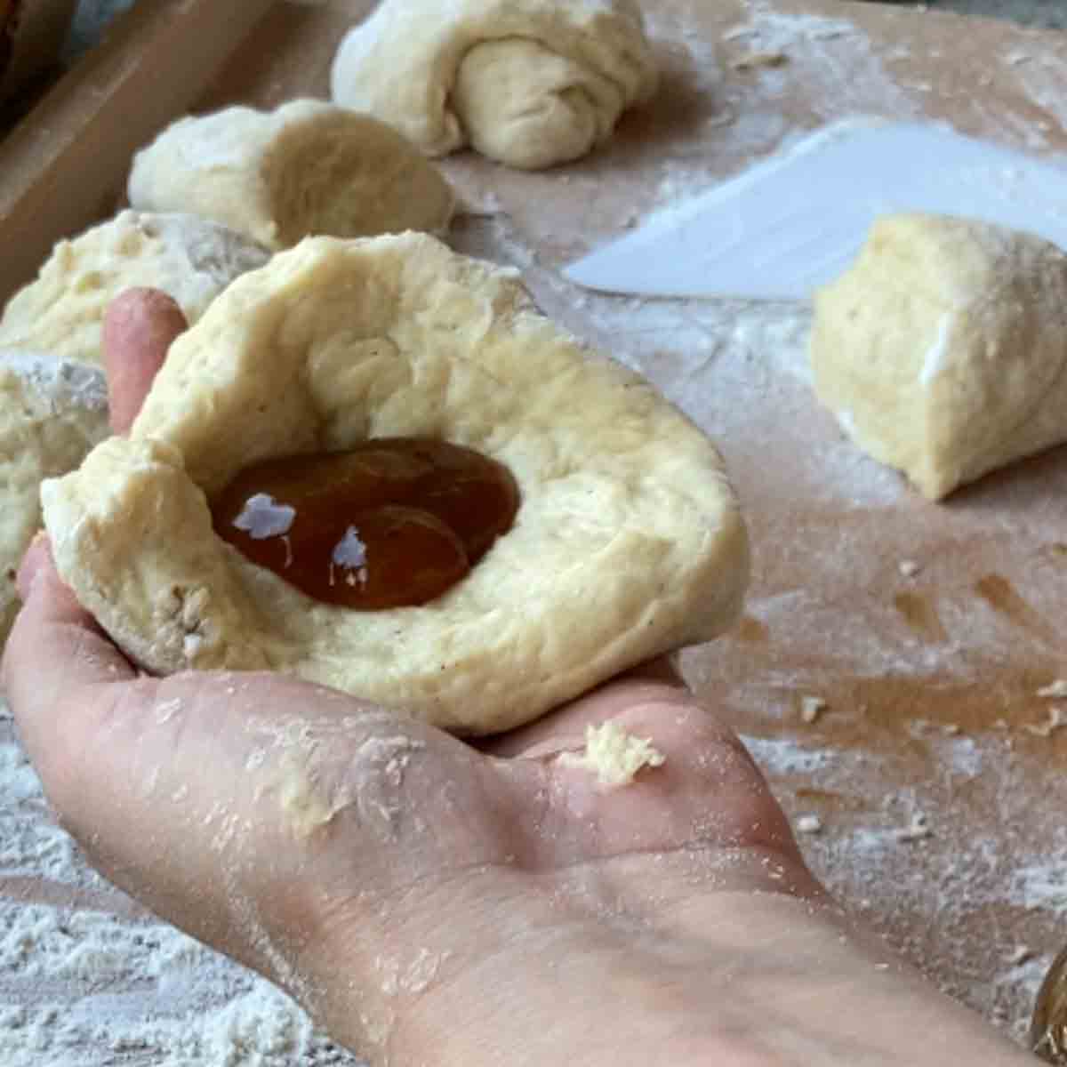 Genaue Anleitung für Buchtel formen: Marmelade auf Teig platzieren.